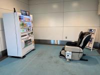 A massage chair pointing at a vending machine in an airport lounge