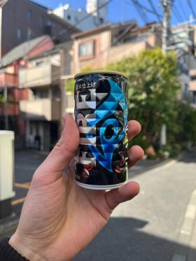 A can of Kirin Black Fire coffee held up against a backdrop of a residential street