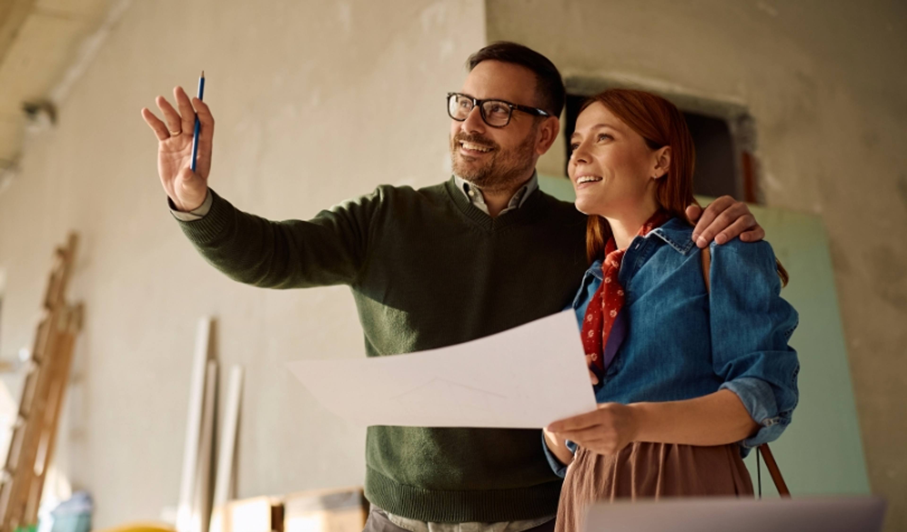 Couple reviewing building plans with their builder during a home walkthrough