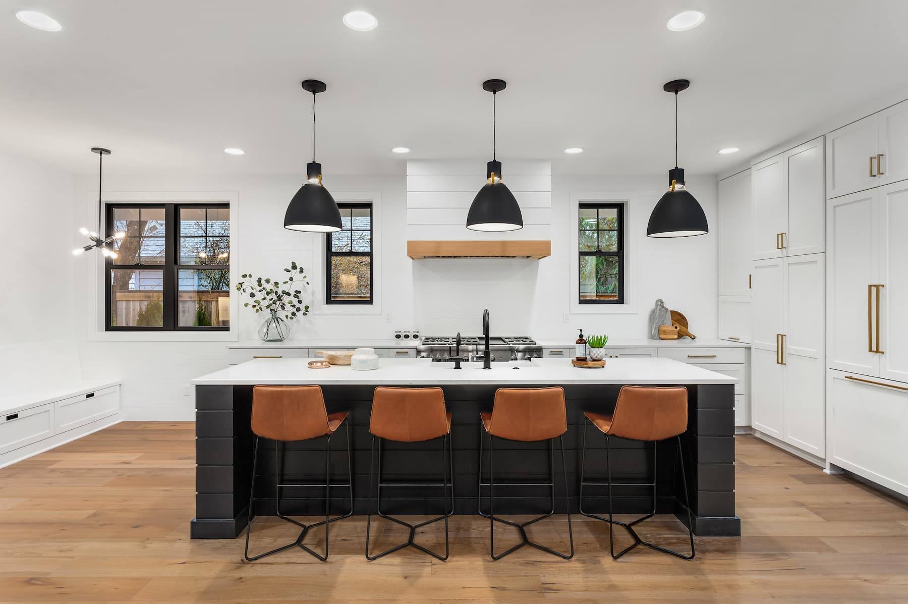 Modern kitchen with large stone island, pendant lighting and white cabinetry