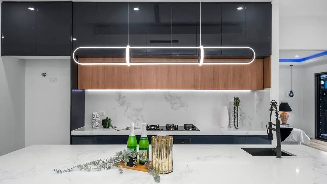 Modern designer kitchen with stone island bench, timber cabinetry and feature pendant lighting.