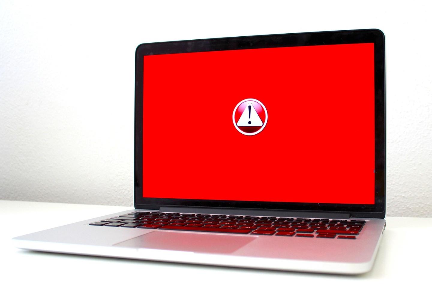 Laptop con la pantalla en rojo y un ícono de advertencia