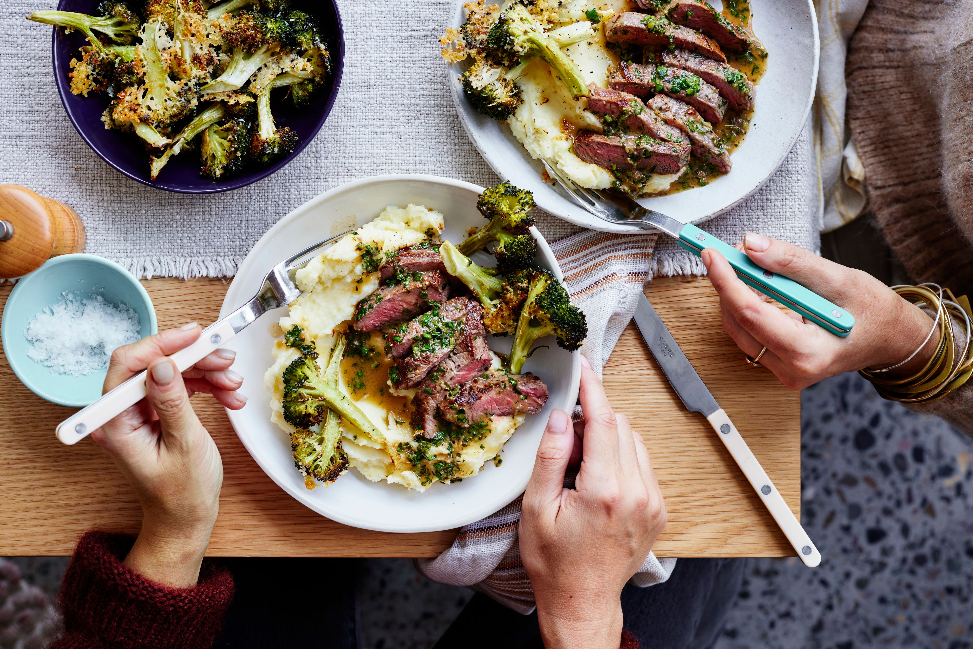 Family together at the dinner table eating steak and mash with broccoli