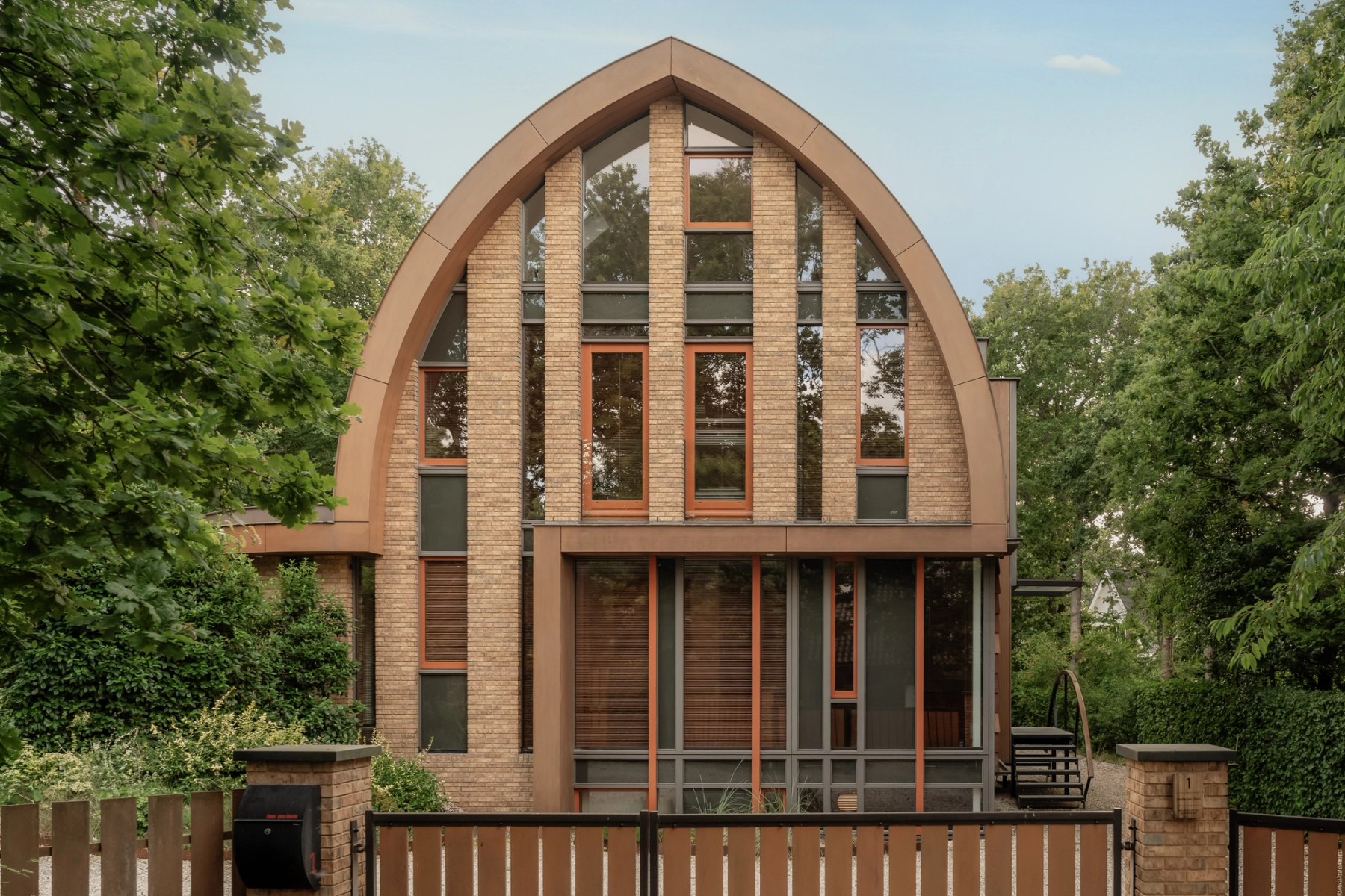 Voorgevel van de villa met spitsboogvormige kap en hoge glaspartijen