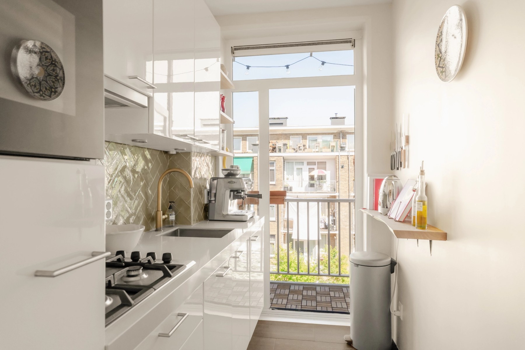 Witte keuken met gasfornuis en openslaande deur naar het balkon
