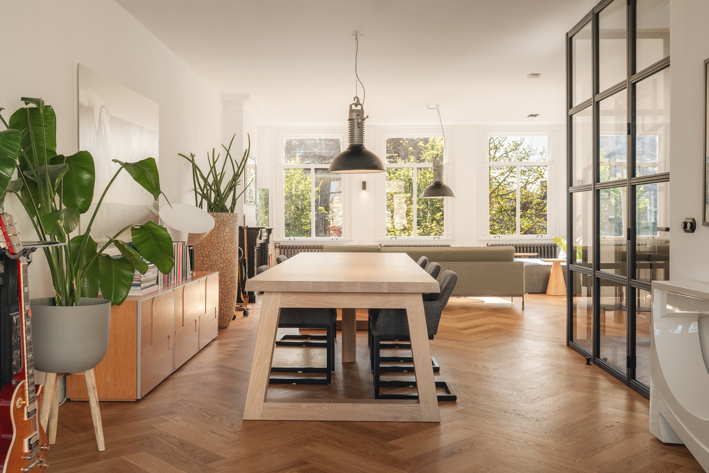 Open woon- en eetkamer met houten eettafel en visgraatvloer aan de Leidsegracht in Amsterdam