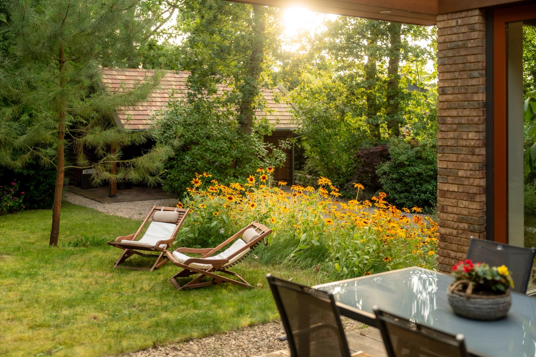 Tuin in de avondzon met ligstoelen en bloeiende borders