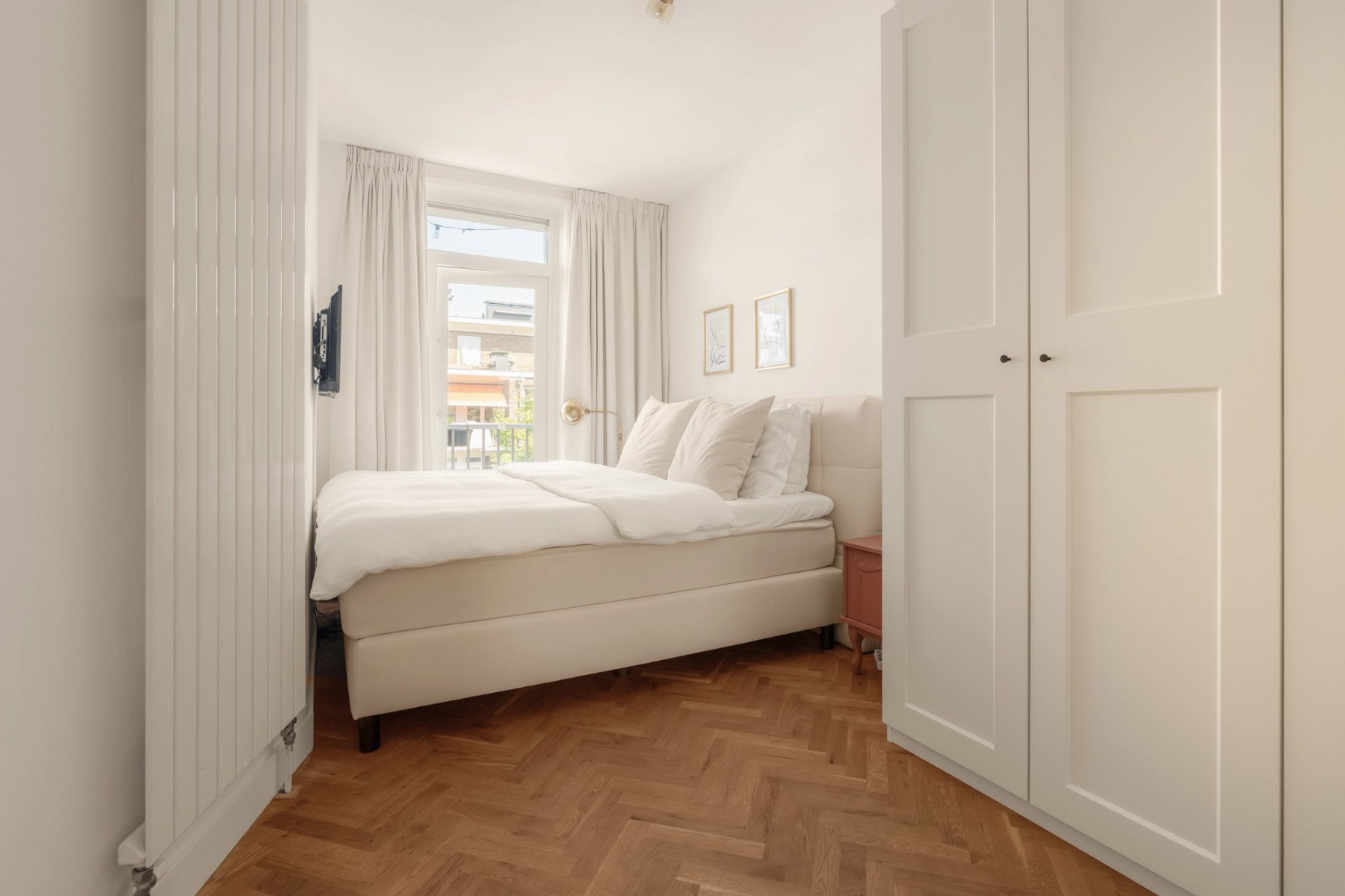 Slaapkamer met tweepersoonsbed, inbouwkast en raam met vitrage