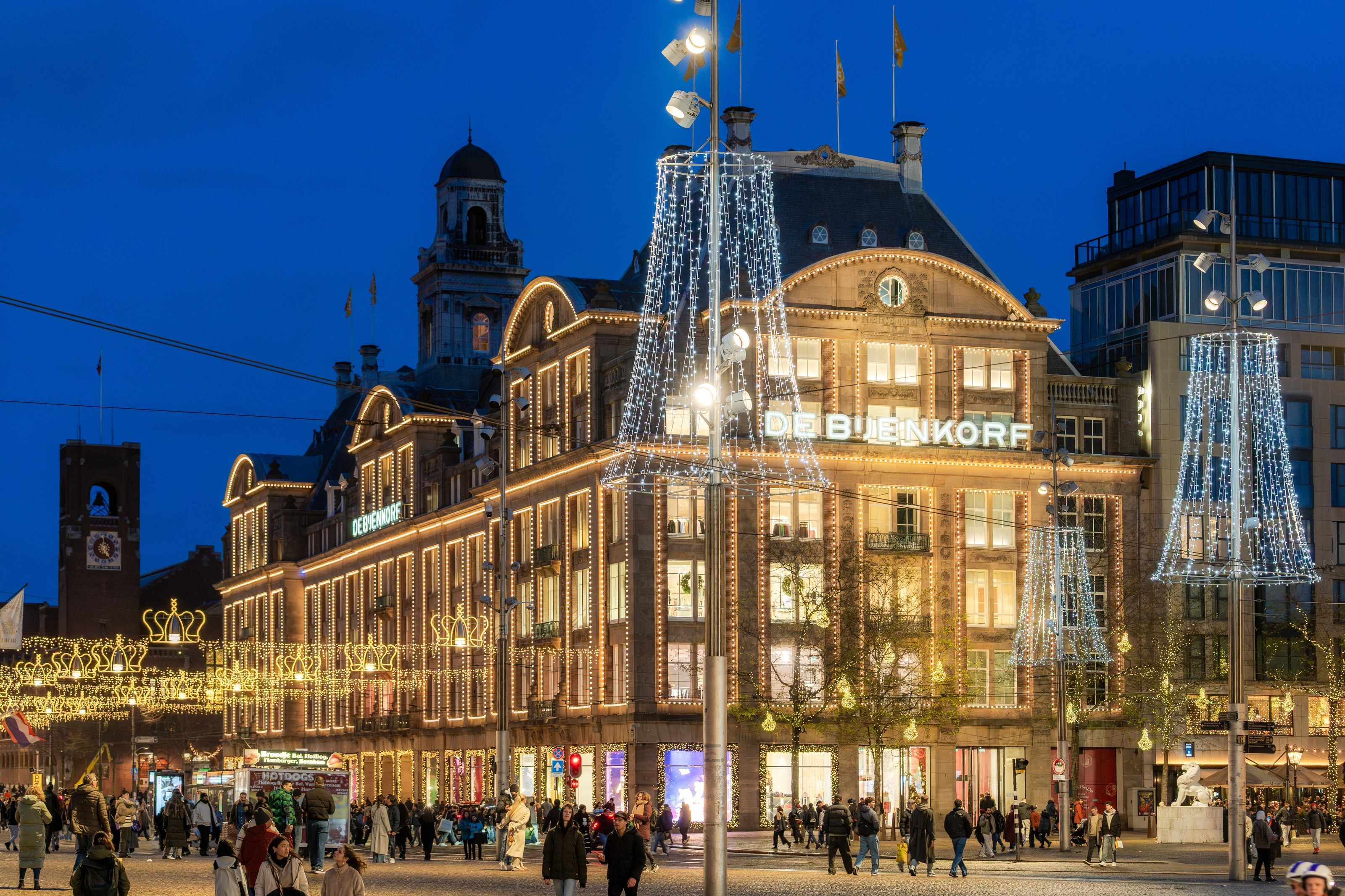 Kegels van wit licht op de Dam en de verlichte gevel van De Bijenkorf