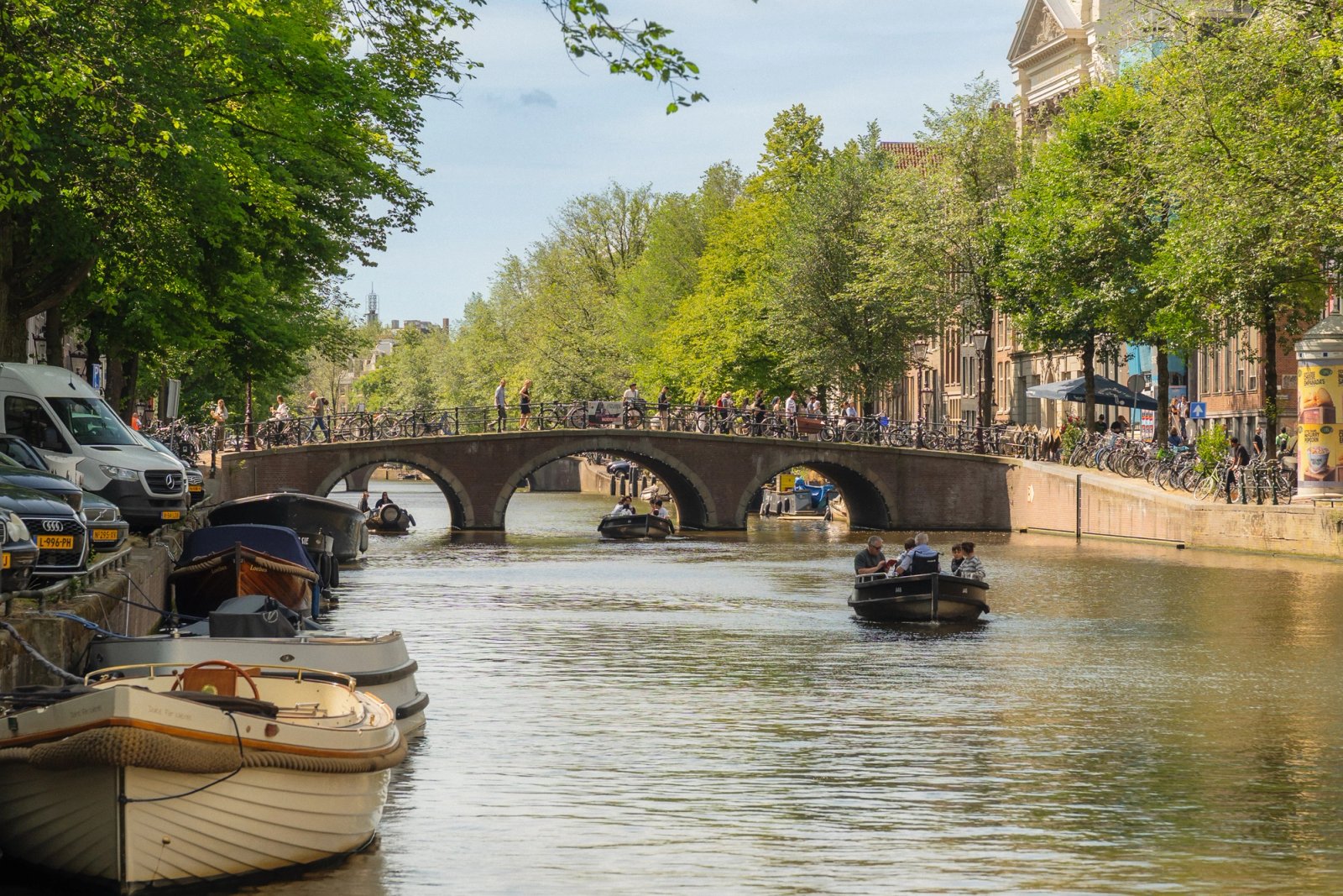 Sloepen op een Amsterdamse gracht bij een stenen boogbrug