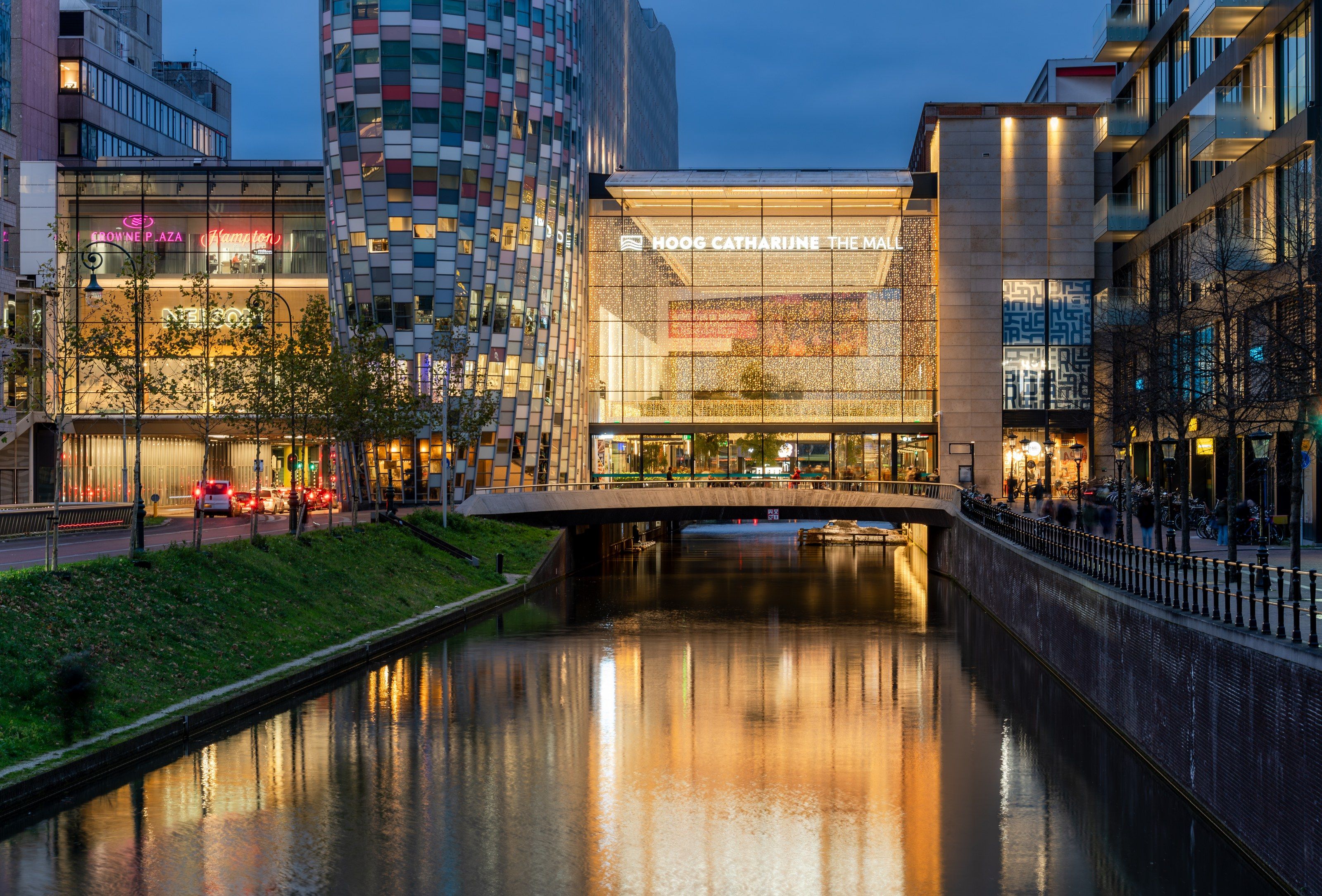 Glazen entree van Hoog Catharijne vanaf de gracht in de schemering