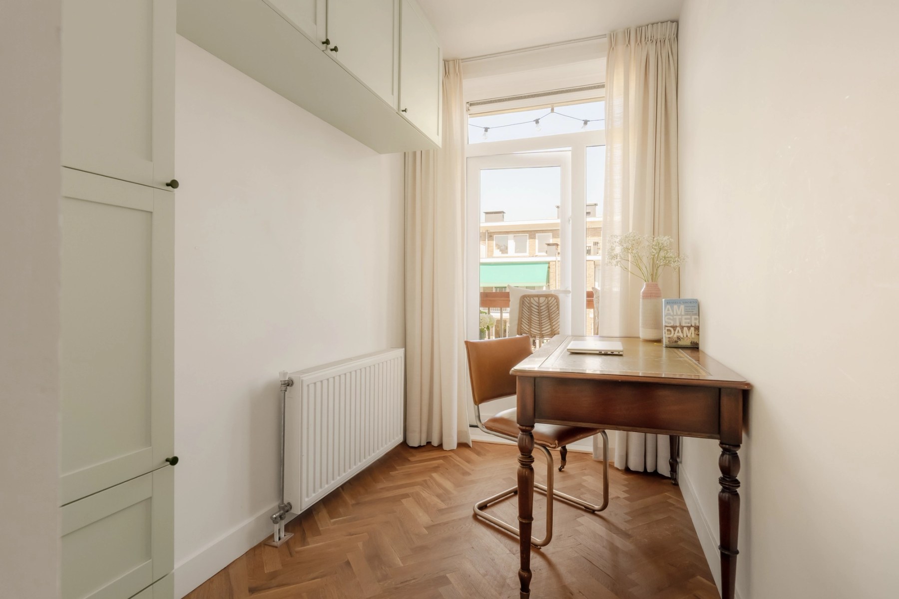 Werkkamer met houten bureau bij het raam en visgraatvloer