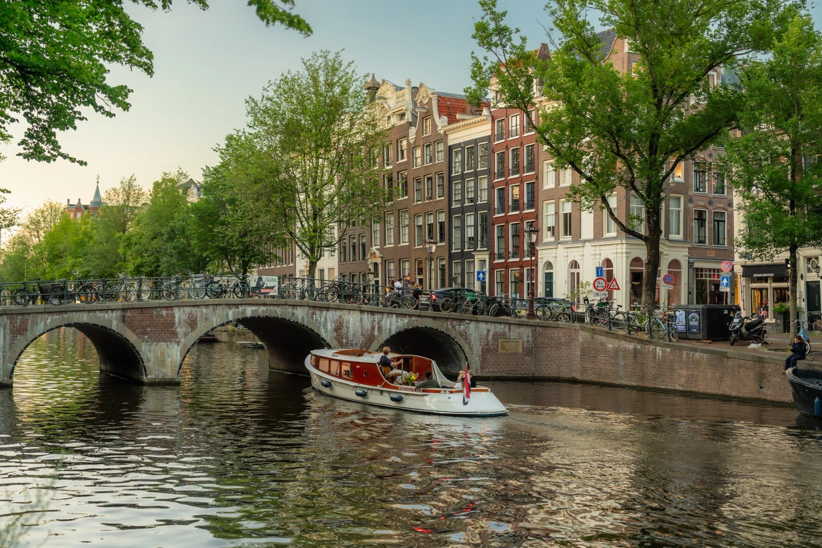 Salonboot vaart onder een brug door op een Amsterdamse gracht met grachtenpanden