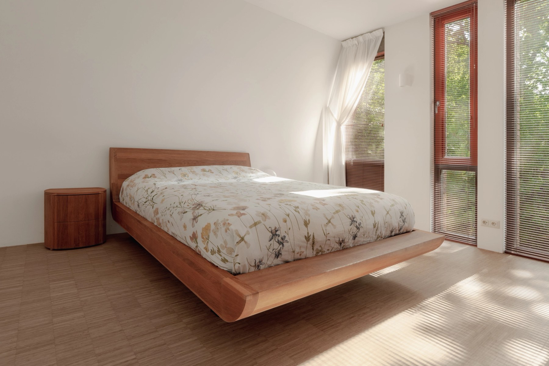 Slaapkamer met houten bed en hoge ramen