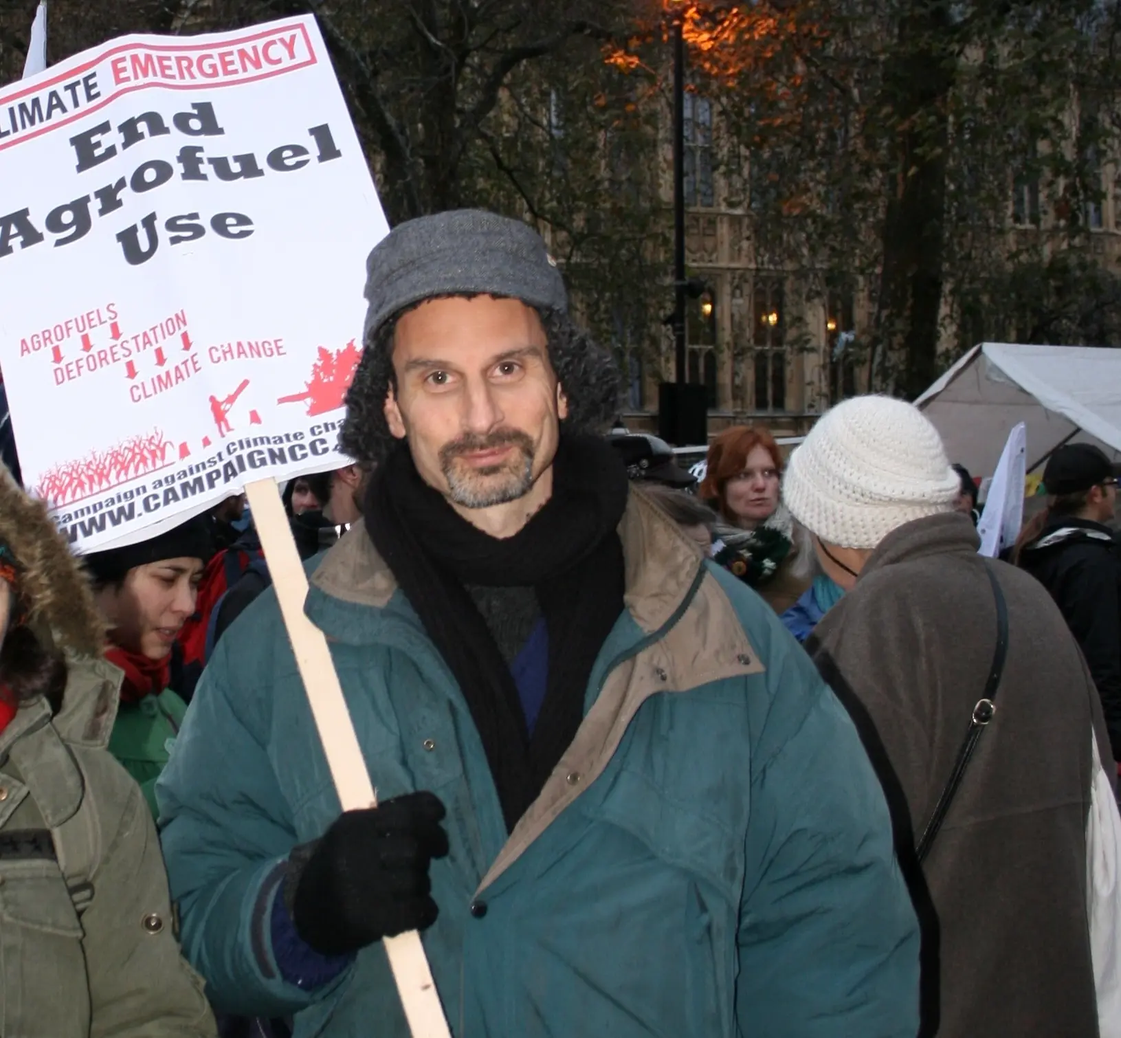 Rob in a hat with earflaps holding placard on demo: 'End Agrofuel Use'