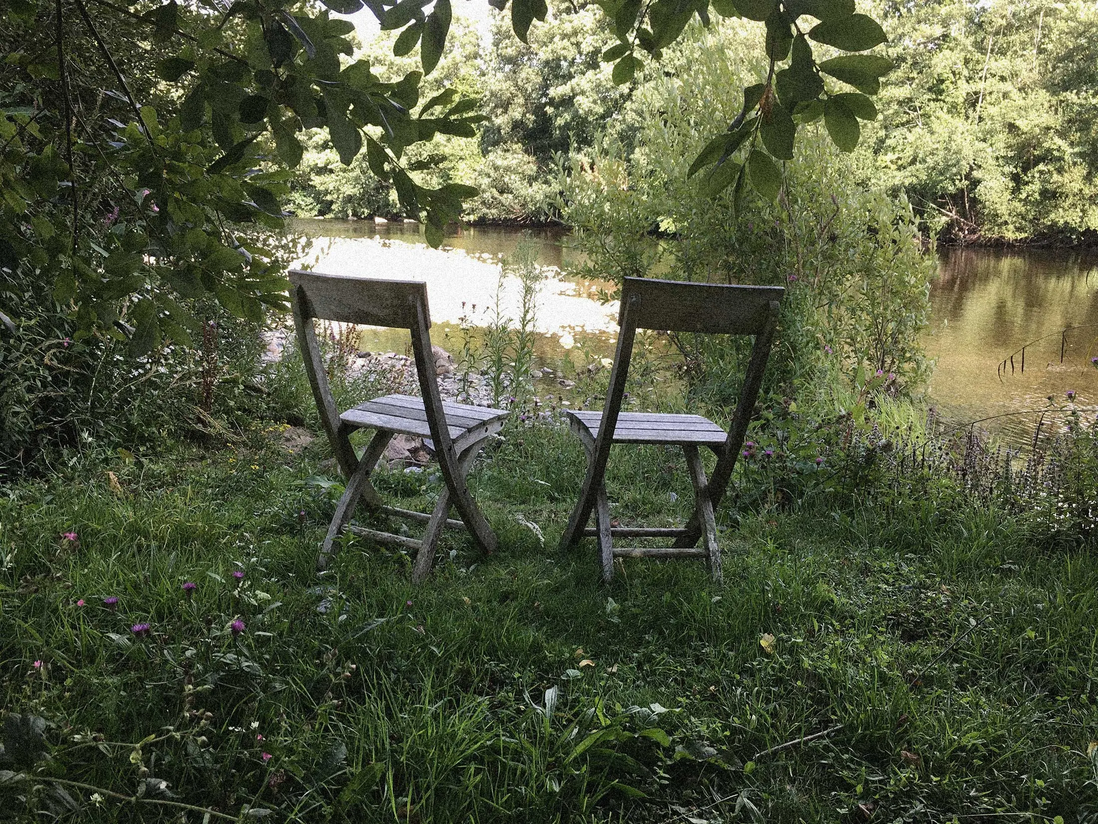 photo of two empty adjacent wooden chairs on the river bank where Rob lived
