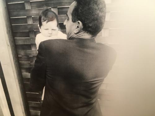 old photo of Rob's dad in suit with back to camera holding baby Rob looking over his shoulder