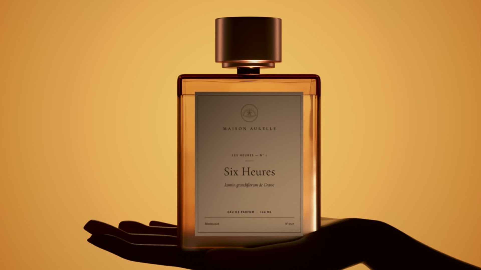 Affiche Maison Aurelle : un flacon ambré à bouchon cuivré posé à plat sur la paume d’une main en silhouette noire. Fond dégradé ambre et orangé, logo et nom de la maison en haut.