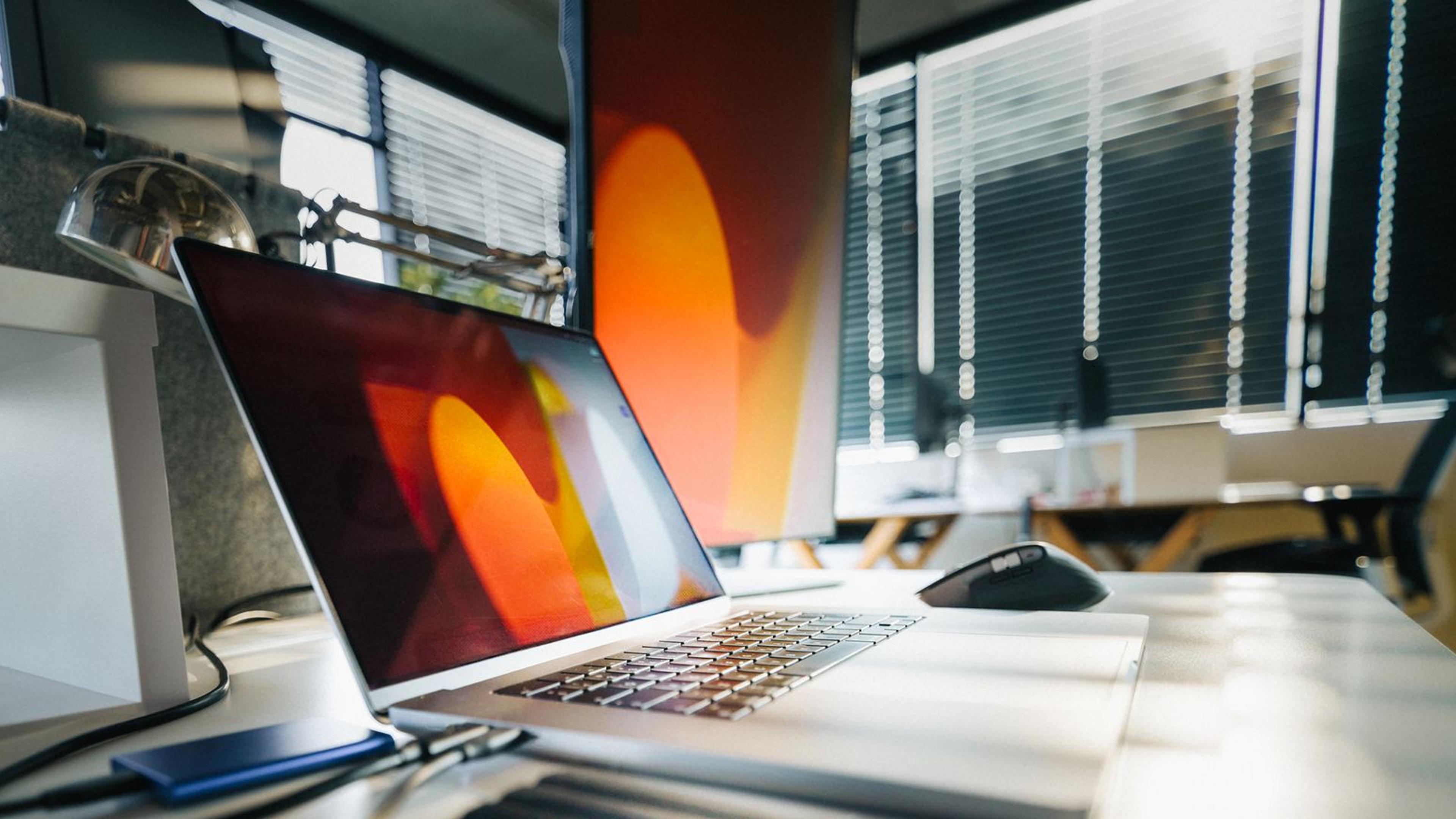A laptop and external storage drives on an office desk