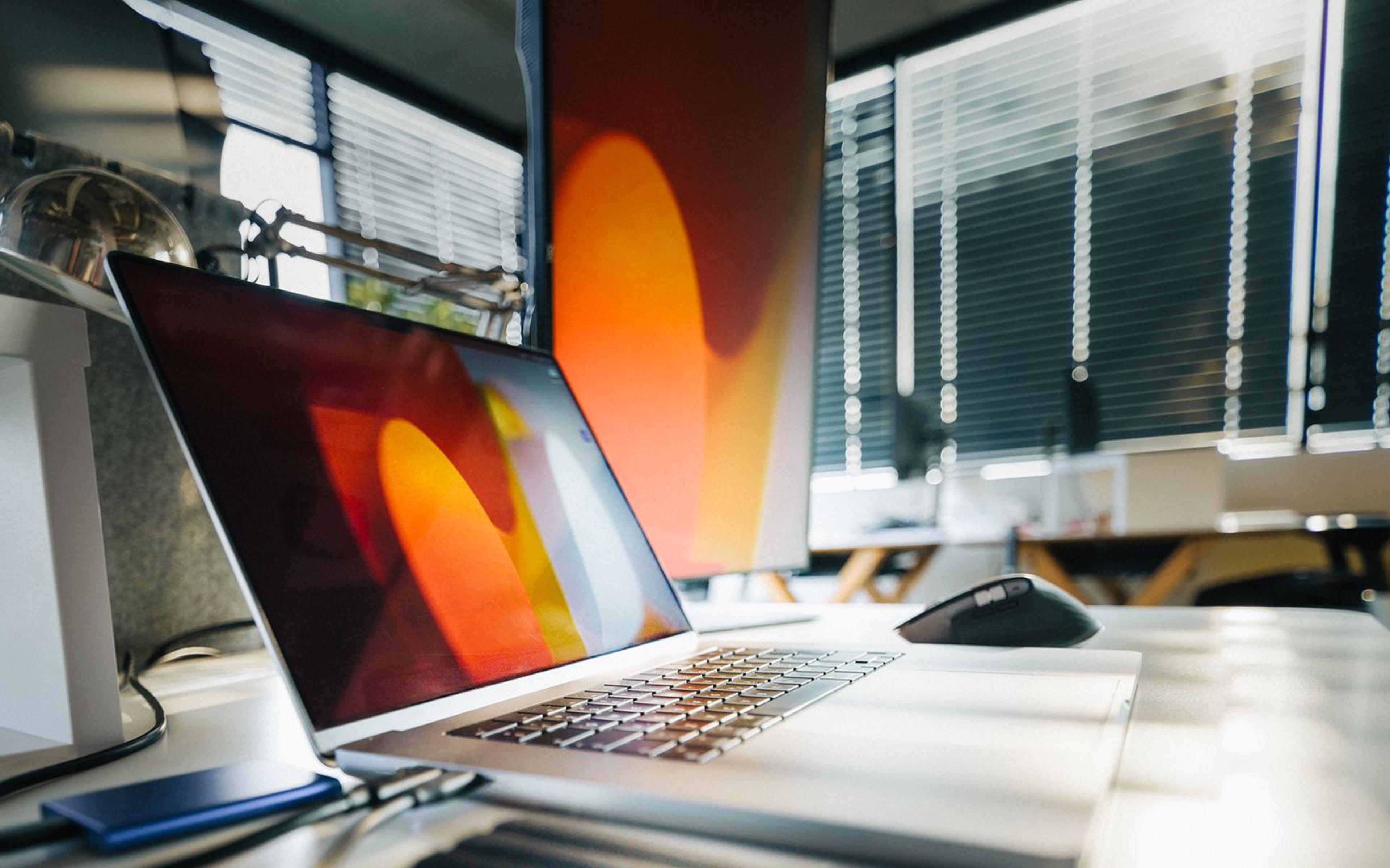 A laptop and external storage drives on an office desk