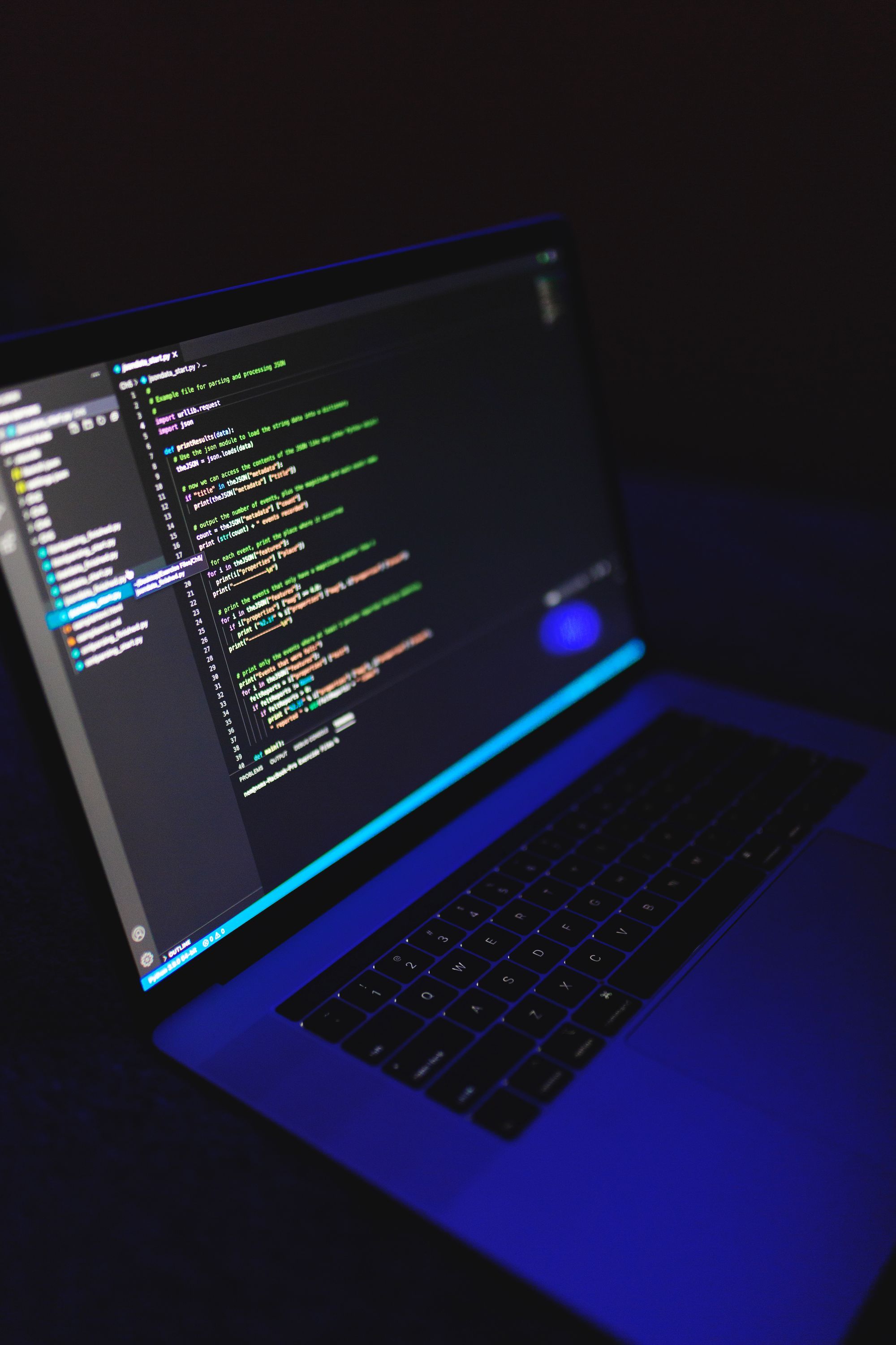 A laptop showing code in a dark workspace