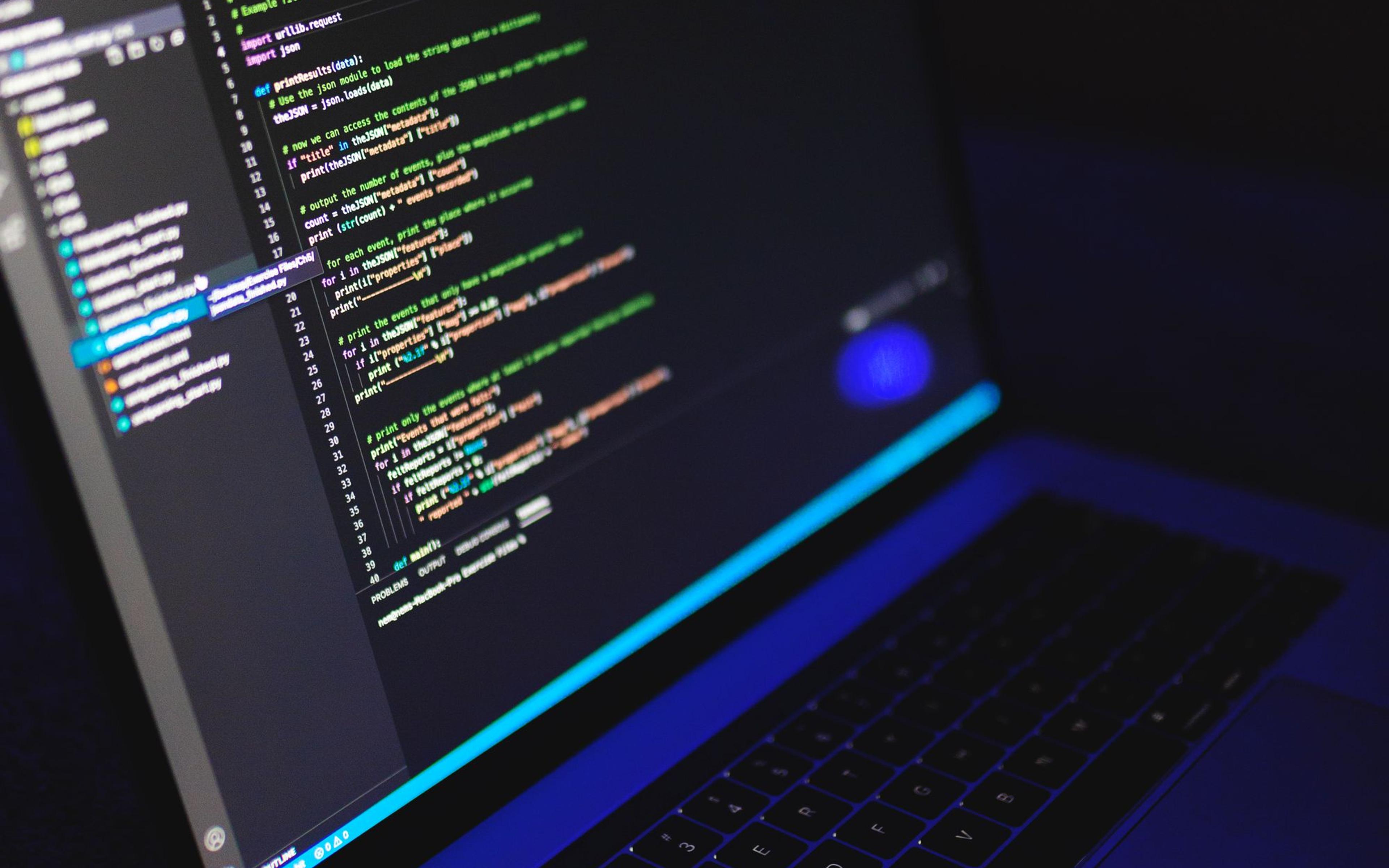 A laptop showing code in a dark workspace