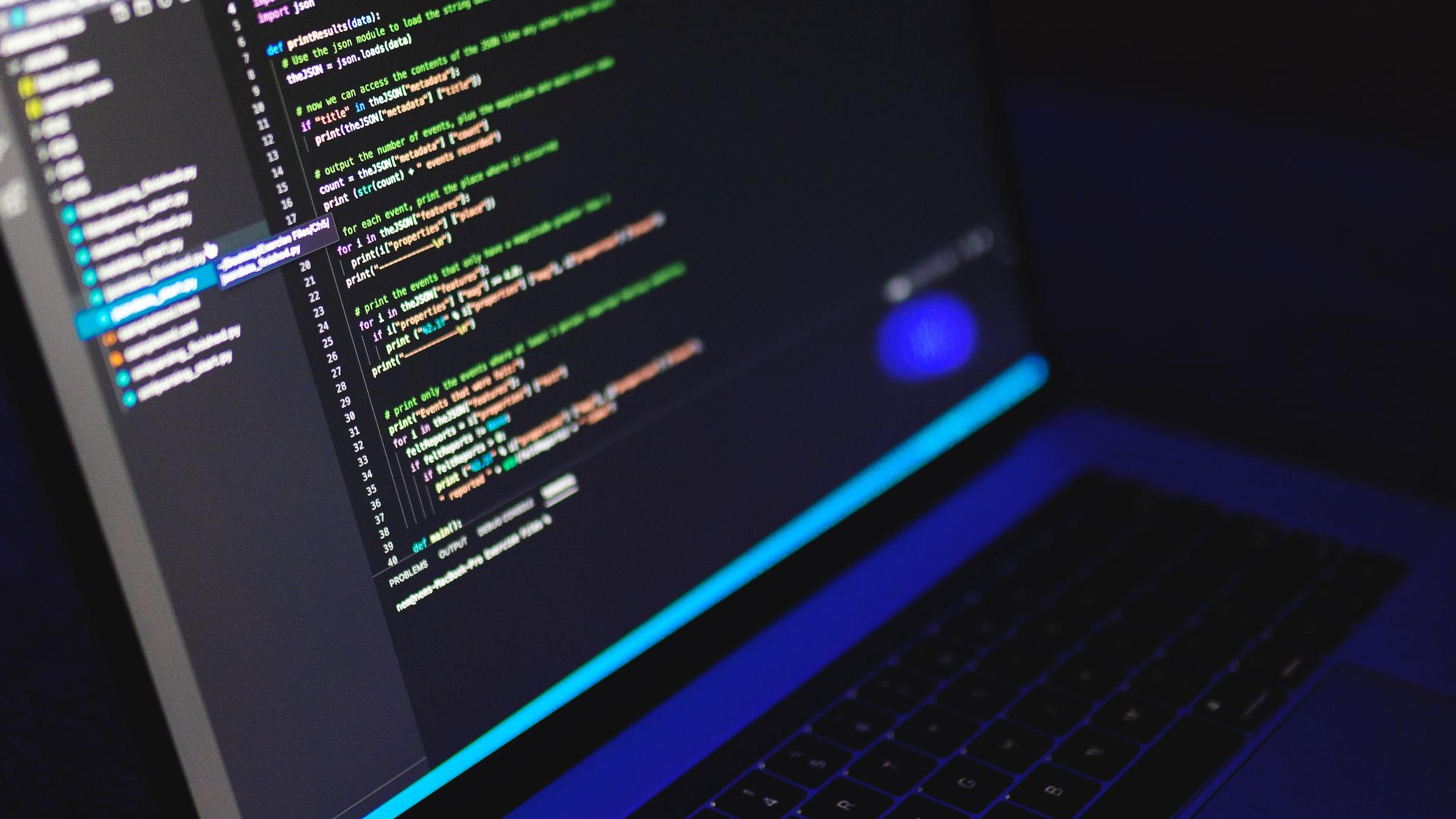 A laptop showing code in a dark workspace