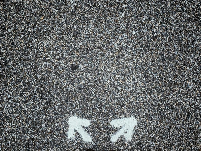 pavement with chalk arrows going in two directions black shoes and pants