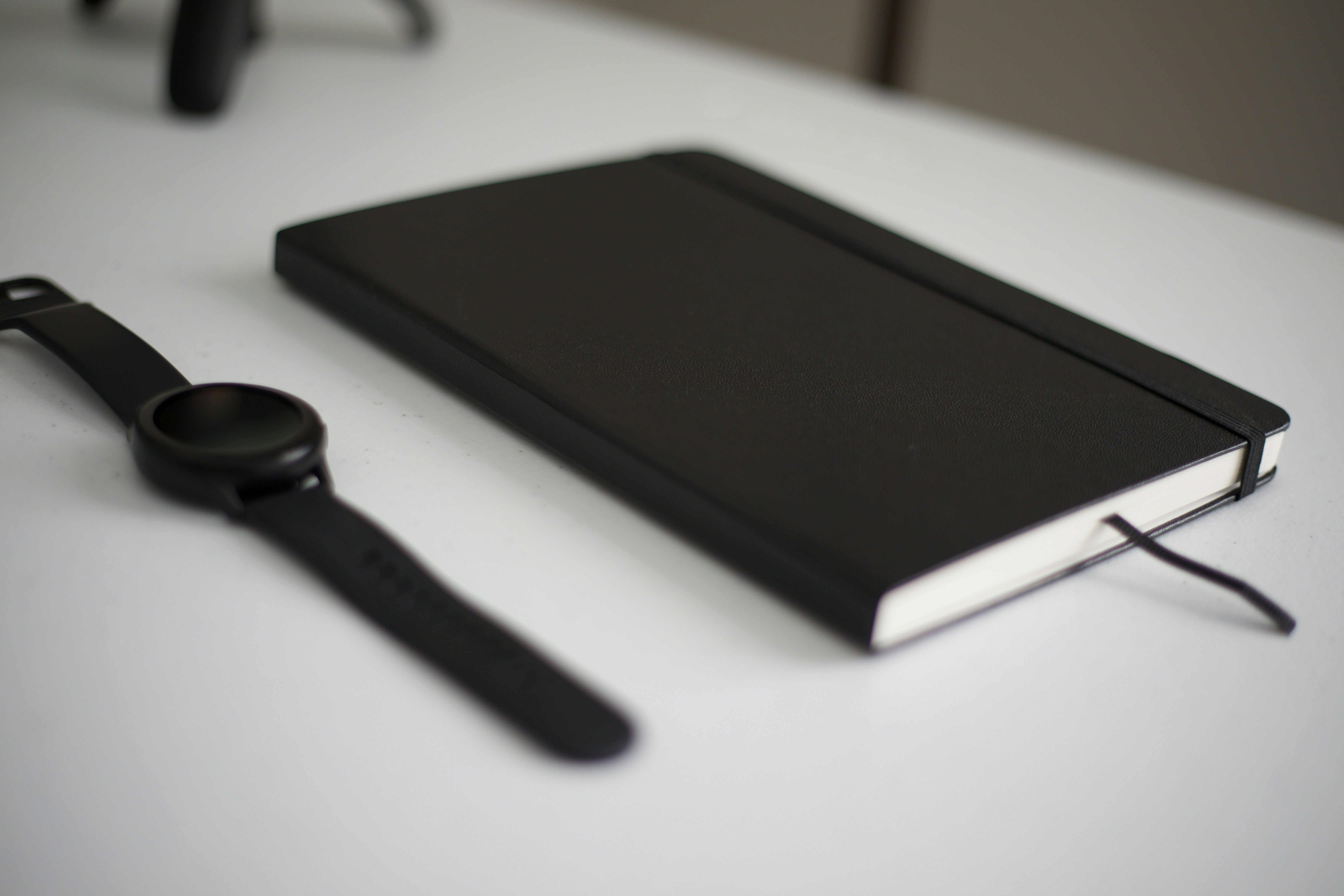 A black book and a watch on a table