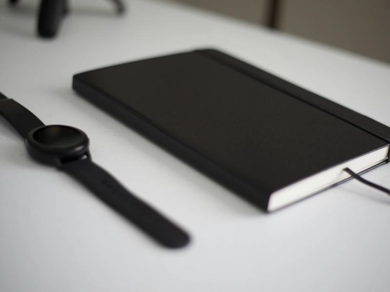 A black book and a watch on a table