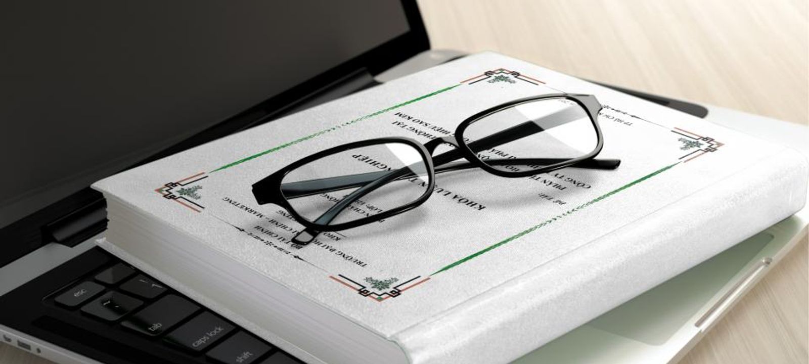 Lesebrille liegt auf einem aufgeschlagenen Buch neben einem Laptop
