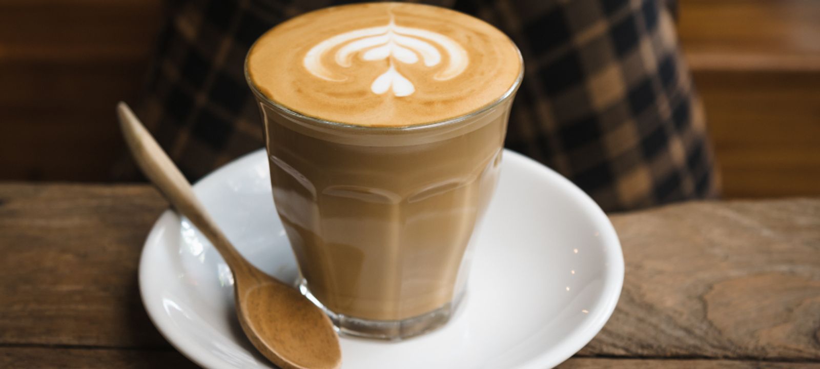 Cappuccino mit Milchschaum-Muster auf einem Holztisch