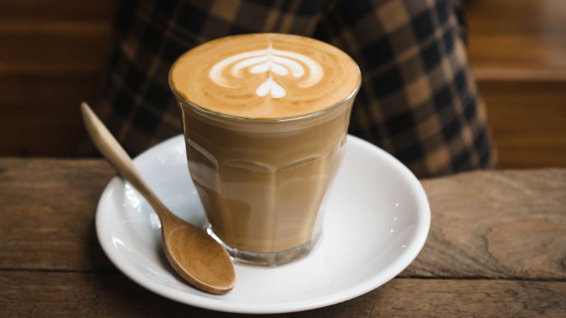 Cappuccino mit Milchschaum-Muster auf einem Holztisch