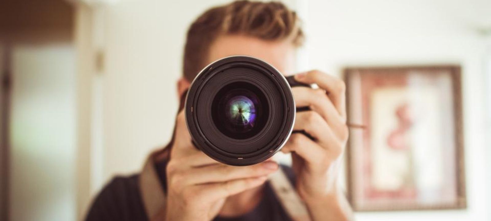 Mann fotografiert mit einer Spiegelreflexkamera direkt in die Kamera