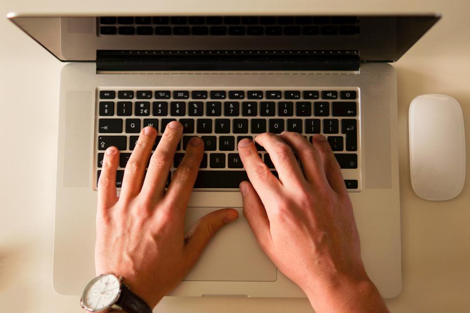 Hände tippen auf der Tastatur eines Laptops