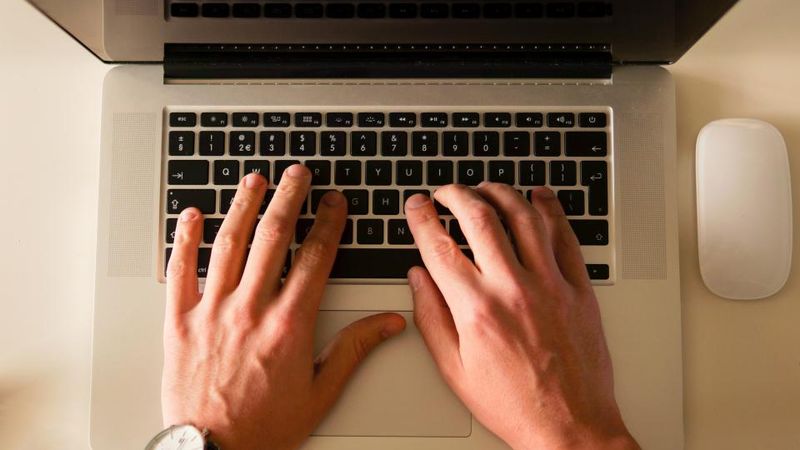 Hände tippen auf der Tastatur eines Laptops