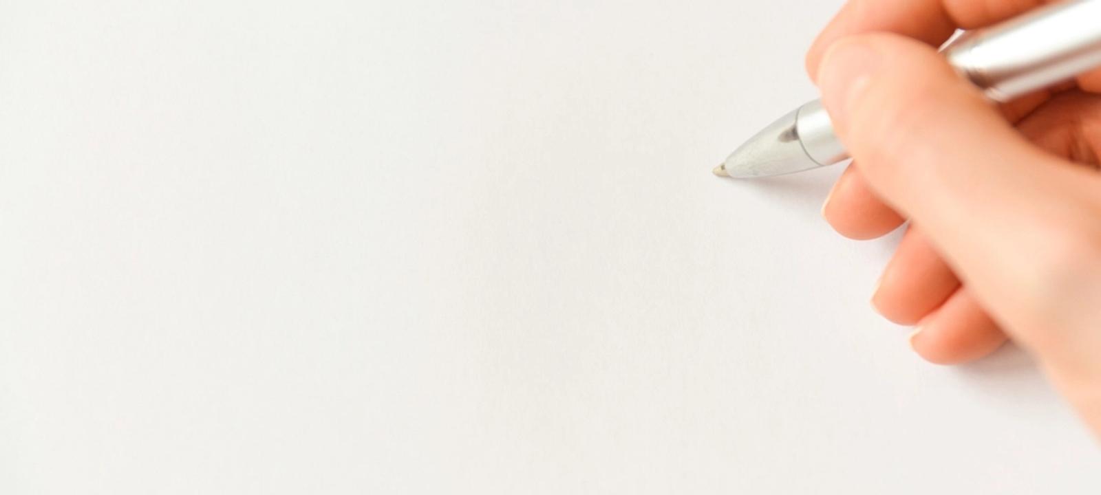 Hand mit Stift über einem leeren weißen Blatt Papier