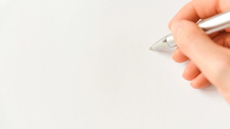 Hand mit Stift über einem leeren weißen Blatt Papier