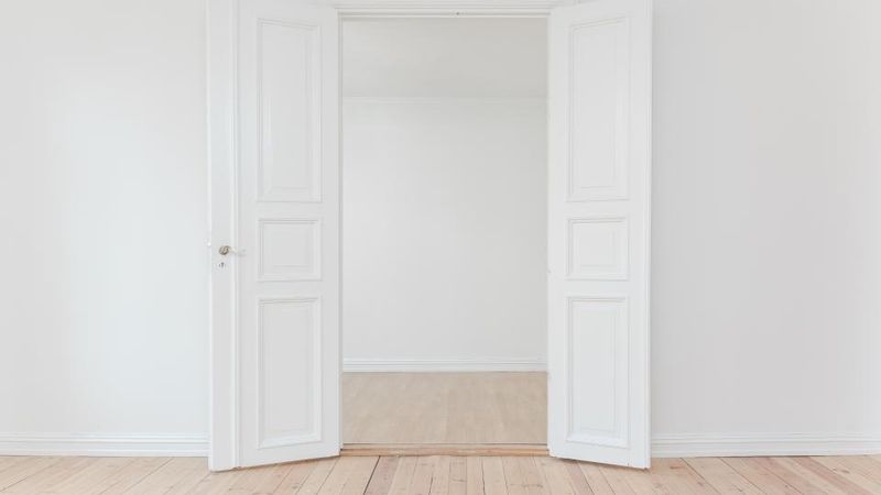 Offene weiße Tür in einem hellen, leeren Raum