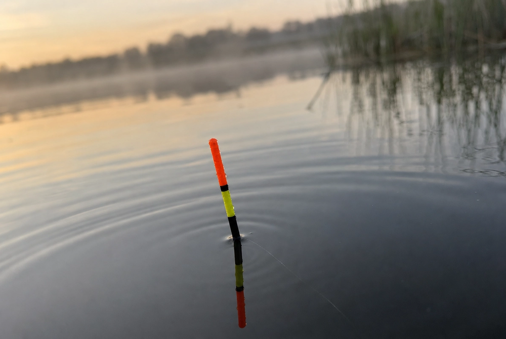 Waggler float with only coloured tip showing above calm lake surface