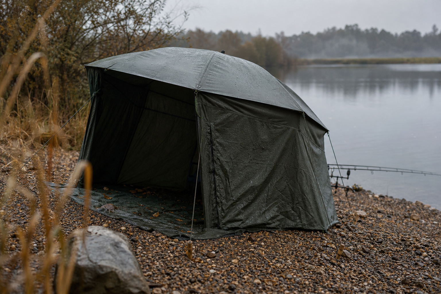 Compact brolly shelter with fabric side panels beside a calm grey lake