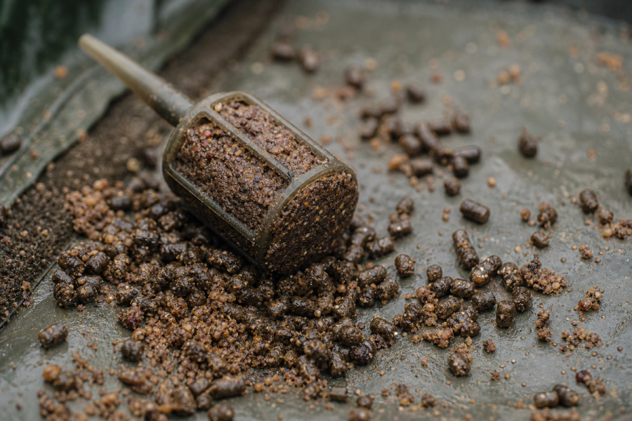 Close-up of a loaded method feeder surrounded by dampened micro pellets on a mat
