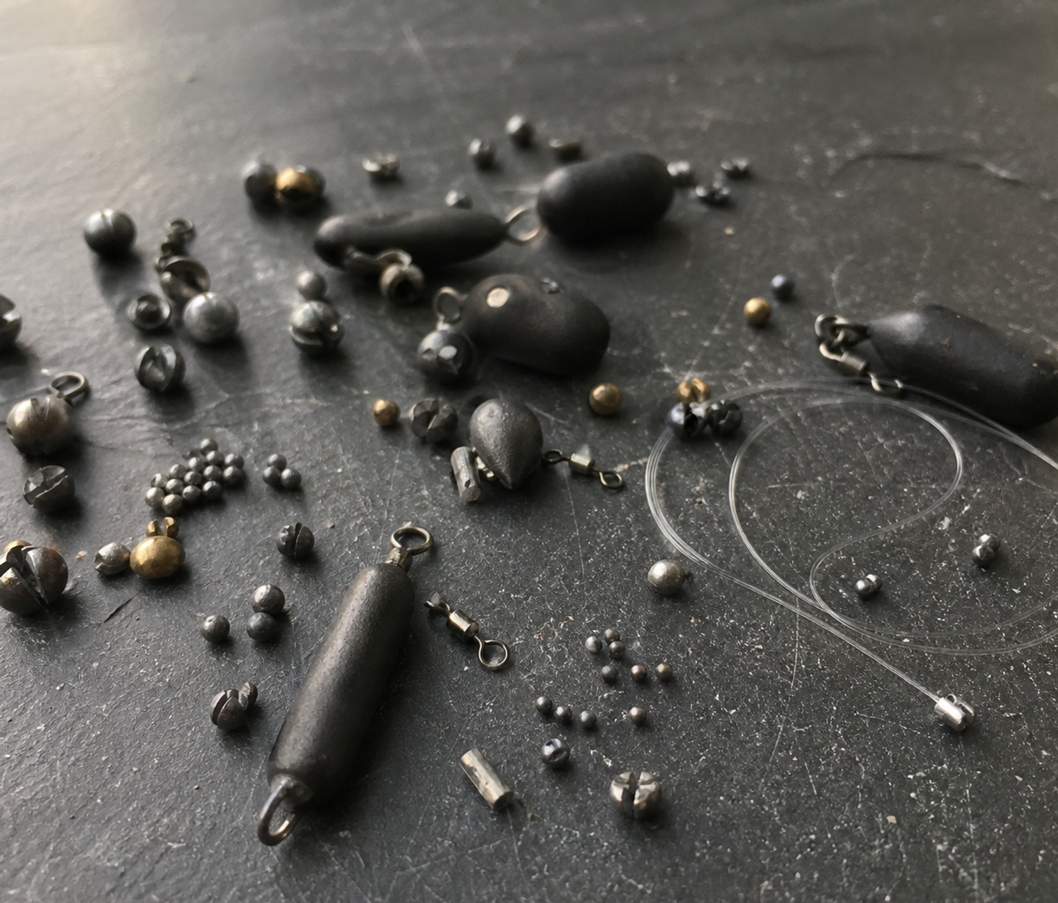 Assorted non-lead fishing shot and leger weights arranged on a dark surface