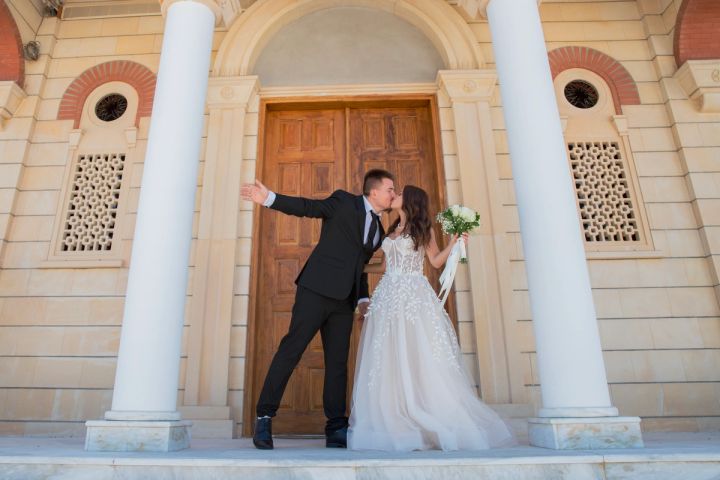 Playful bride and groom posing at the wooden church doors on their Cyprus wedding day