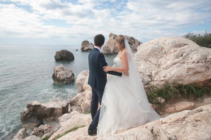 Bride and groom on the rocks by the sea in Paphos