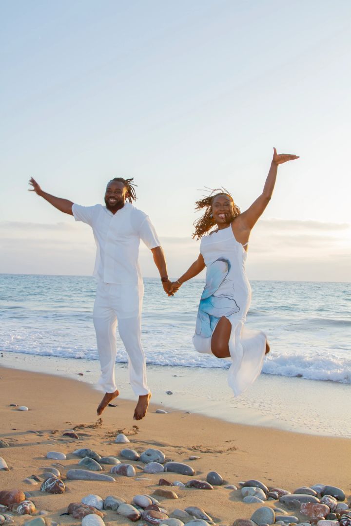 Joyful couple jumping and holding hands on a Cyprus beach at sunset