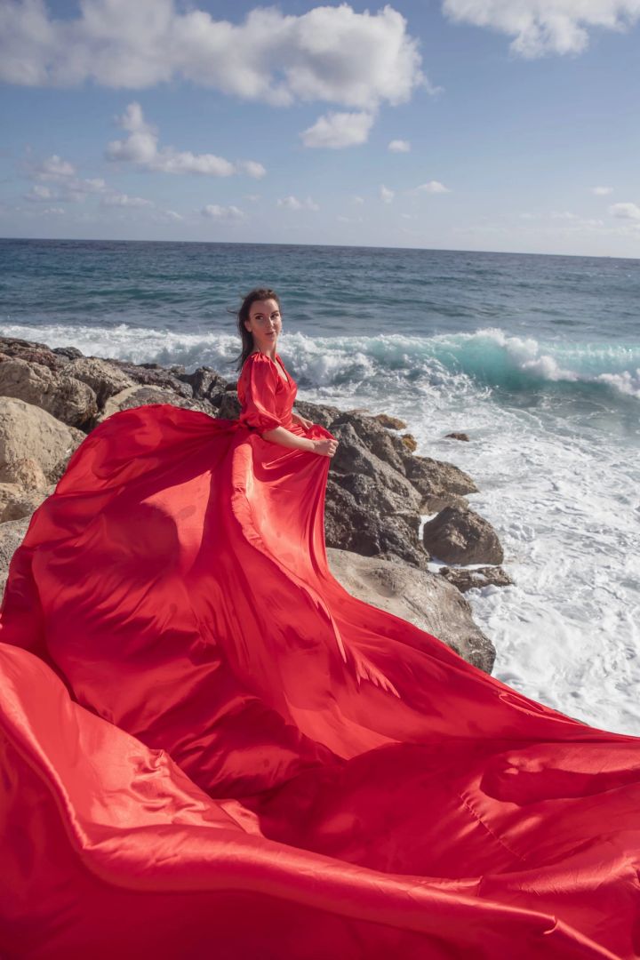 Flying dress photography in a red dress by the sea in Cyprus