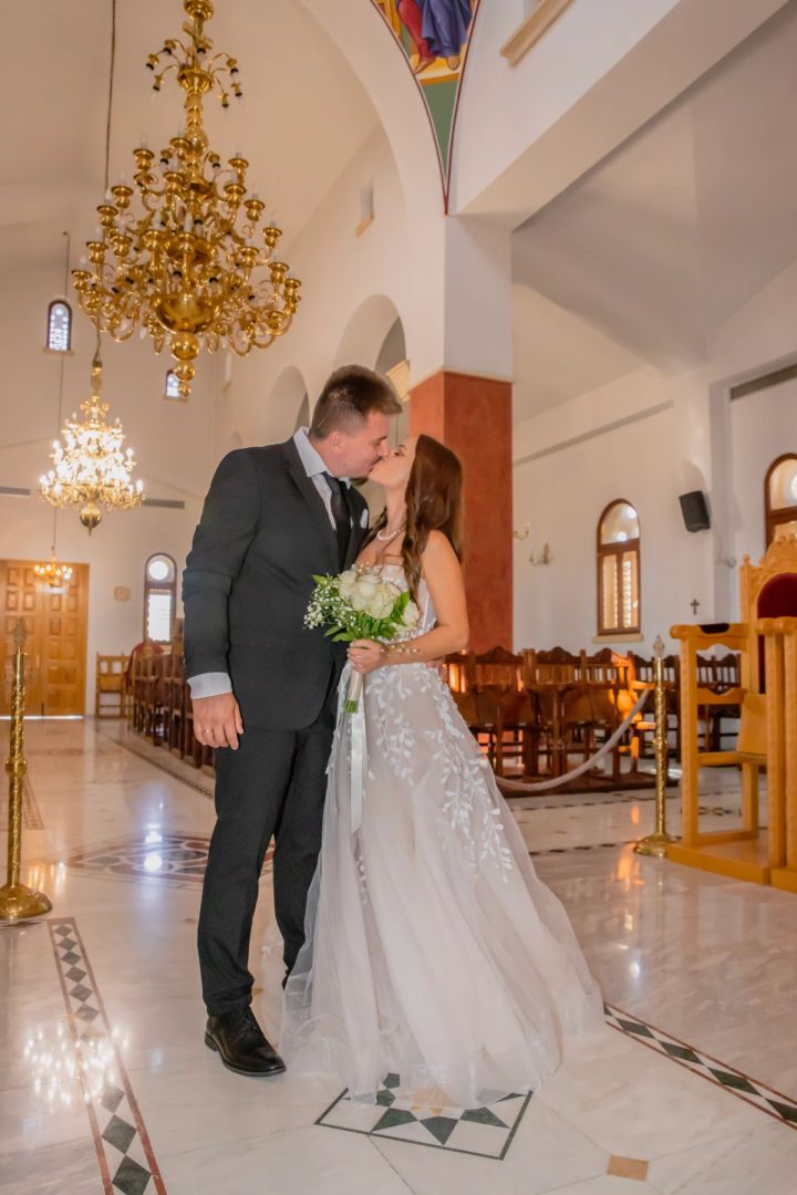 Bride and groom sharing a kiss inside an ornate church after their ceremony in Cyprus