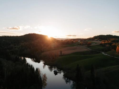 Dronebilde over kulturlandskap i Telemark, med flytende badstueflåte i solnedgang