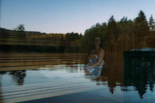 Dame sittende på badstubenk med refleksjoner av vann i vinduet